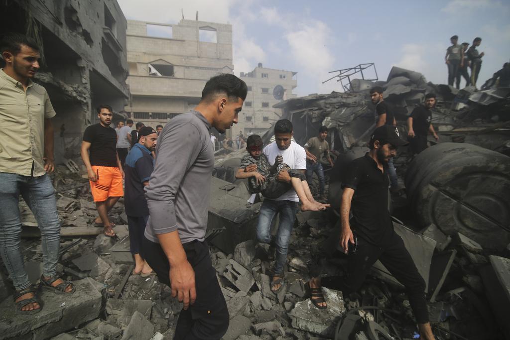 加沙居民在瓦礫堆中救出受傷兒童。(美聯社)