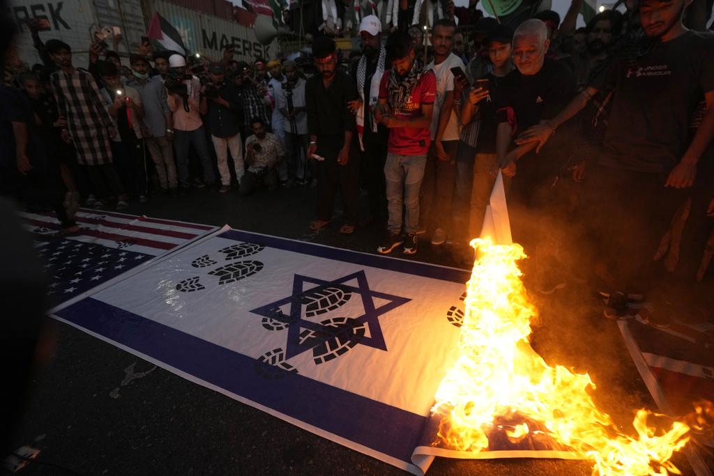 巴基斯坦民眾在集會中焚燒以色列及美國國旗。(美聯社)