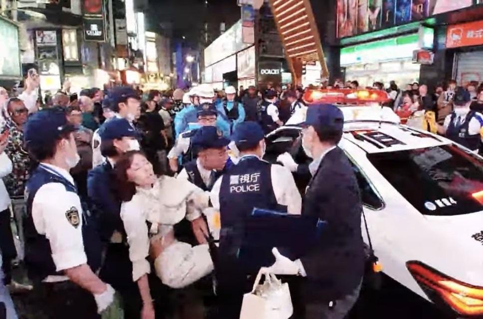 女子暈倒後被警察抬上警車。(X)