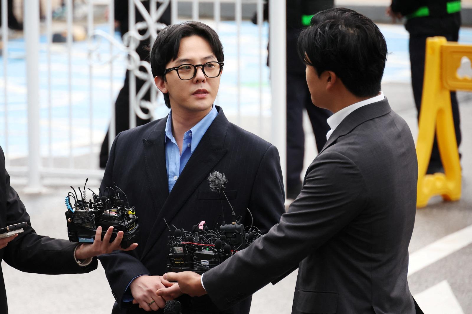 G-DRAGON涉毒現身警局助查150警恭候,近百記者圍影GD進入警局。(路透社)