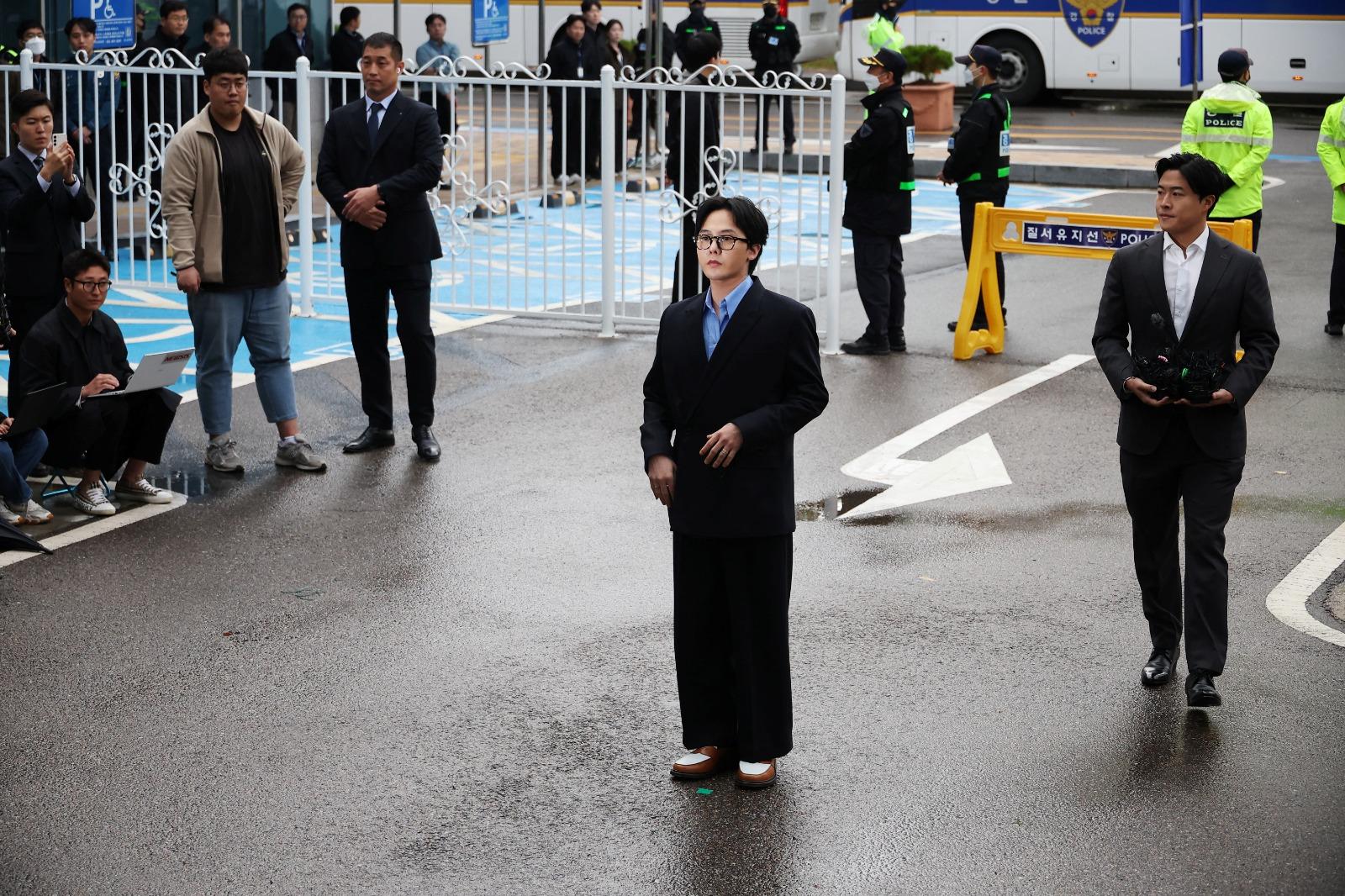 G-DRAGON涉毒現身警局助查150警恭候,近百記者圍影GD進入警局。(路透社)