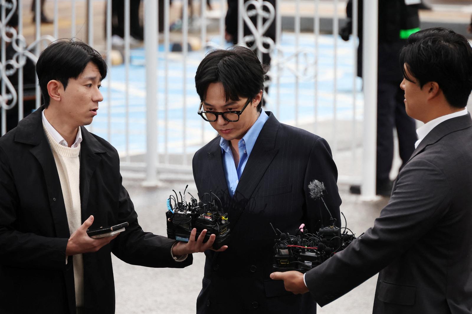 G-DRAGON涉毒現身警局助查150警恭候,近百記者圍影GD進入警局。(路透社)