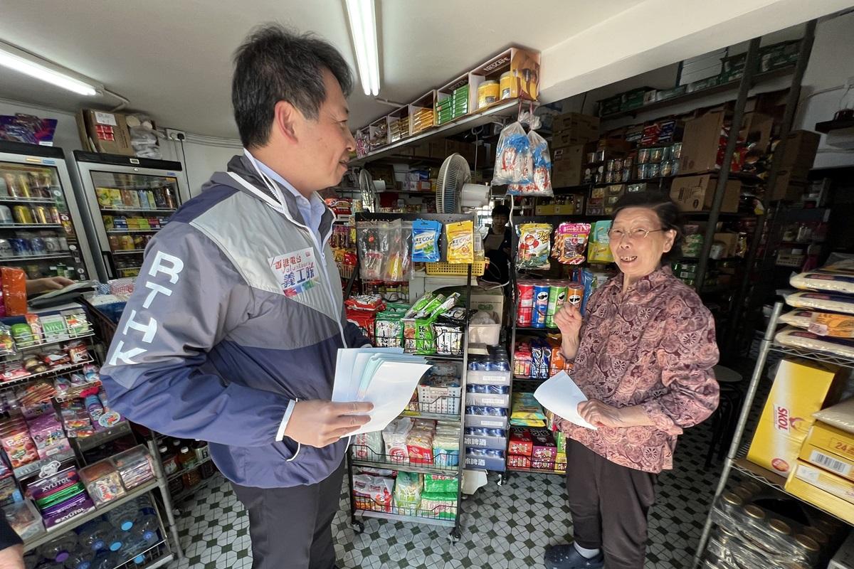 張國財(左)向屯門商戶派發區議會選舉宣傳單張。(港台提供)