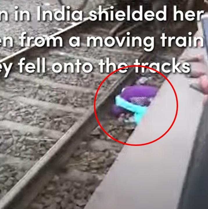 母親毫不猶疑以肉身護著2個兒子,他們在路軌旁緊靠一起伏在地面,險象環生。(YouTube)