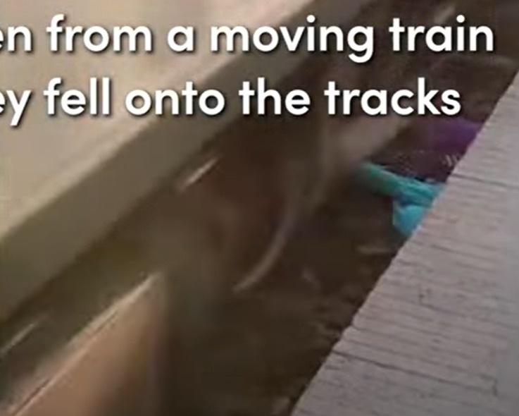 母親毫不猶疑以肉身護著2個兒子,他們在路軌旁緊靠一起伏在地面,險象環生。(YouTube)