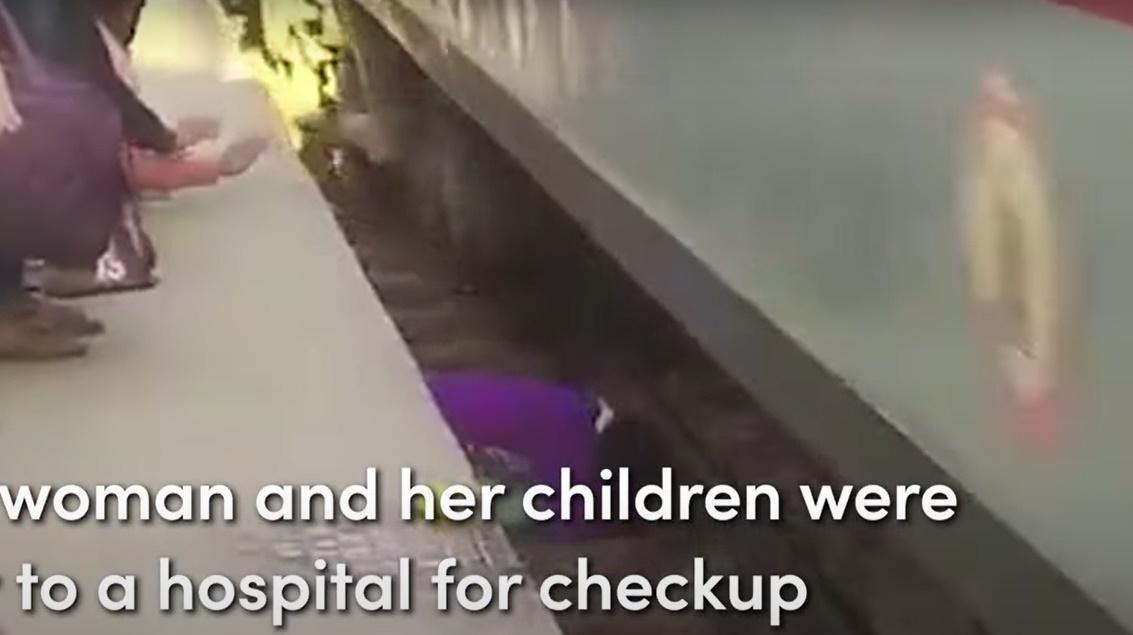 母親毫不猶疑以肉身護著2個兒子,他們在路軌旁緊靠一起伏在地面,險象環生。(YouTube)