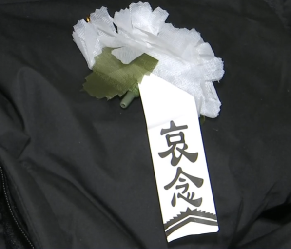 佛山一名男子花費718元人民幣網購一件黑色羽絨服,收到貨後竟在口袋發現白色喪葬胸花,衣服胸口處還疑有佩戴過的痕跡,與店家溝通協商後,對方同意退款退貨並賠償300元(約335港元)。(電視截圖)