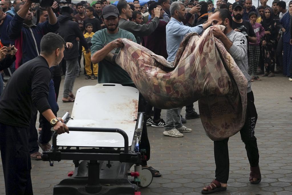 加沙民眾把空襲傷者送到醫院。(美聯社)