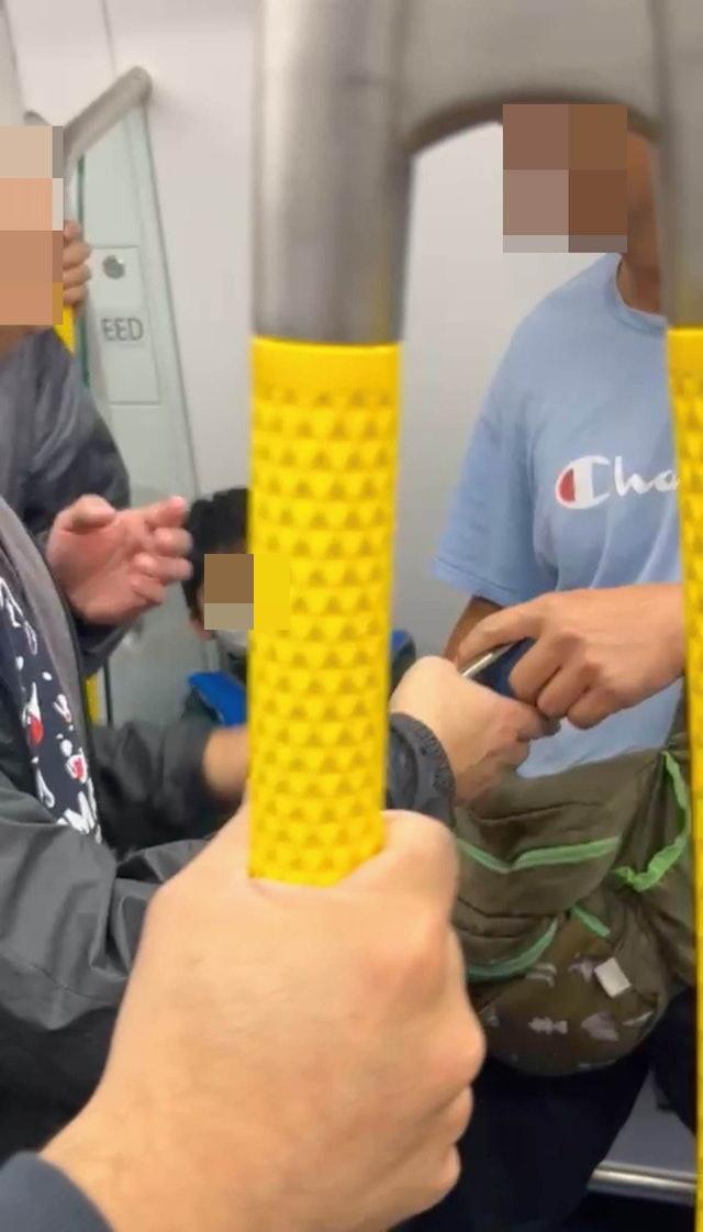 藍衫男疑不忿受襲,一度舉起手機拍攝黑衣男及在場勸架乘客的容貌,惹來在場人士不滿。(網上圖片)