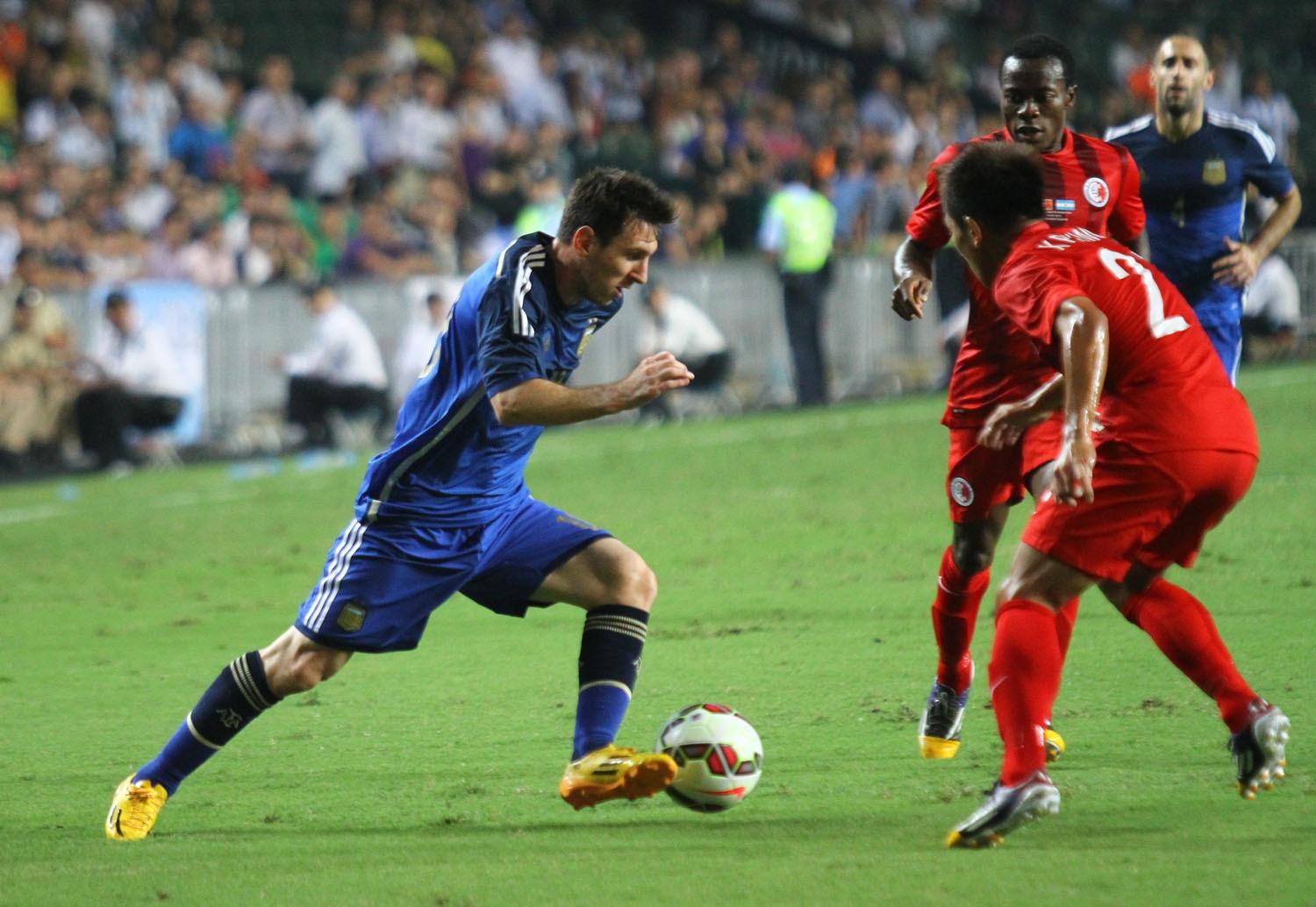 美斯2014年帶領阿根廷以7︰0大勝香港足球隊,圖為球王嘗試向郭建邦盤扭。(資料圖片)