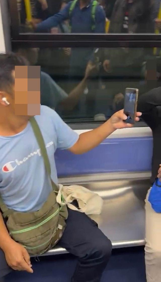 藍衫男疑不忿受襲,一度舉起手機拍攝黑衣男及在場勸架乘客的容貌。(網上圖片)