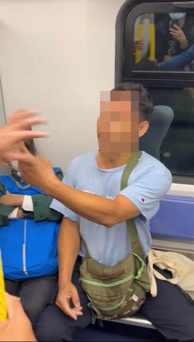藍衫男疑不忿受襲,一度舉起手機拍攝黑衣男及在場勸架乘客的容貌。(網上圖片)