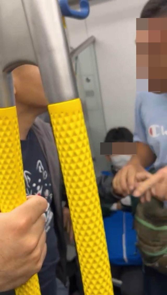 藍衫男疑不忿受襲,一度舉起手機拍攝黑衣男及在場勸架乘客的容貌,惹來在場人士不滿。(網上圖片)