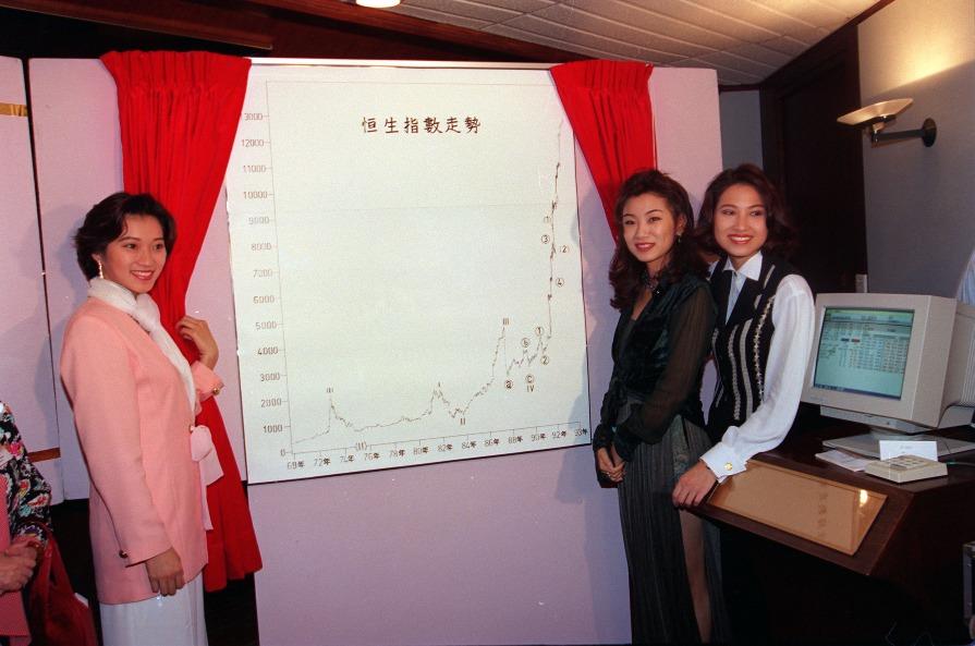 圖片攝於1993年,當年的應屆三甲香港小姐(左起)季軍余少寶、冠軍莫可欣及亞軍林麗薇,為一個財經節目介紹恒生指數走勢圖表。(圖片來源:Getty)