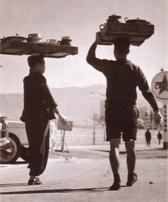 在包伙食盛行的年代,不少運送午飯的人會頭頂着整齊排列的飯餸連碗筷等,準時到工廠、寫字樓等送上美味午膳。(網上圖片)