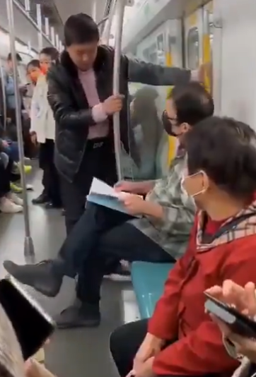 這名戴黑色面罩的外籍男當時坐在北京地鐵4號線車廂座位上安靜看書。此時一名疑似有酒氣的中年男子莫名靠近頻繁挑釁