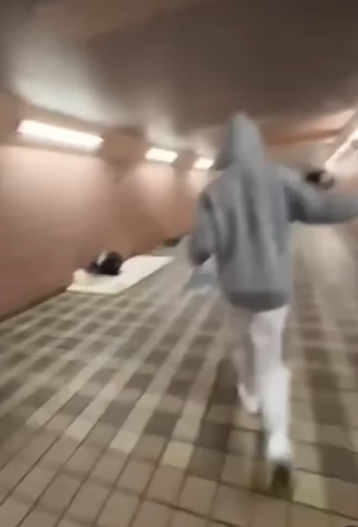 網上流傳影片可見,數名年輕人在跑馬地一條行人隧道向露宿者淋潑清水及可樂後,立即跑走逃去。(網上影片截圖)