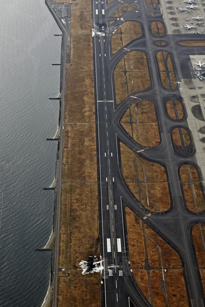 日航客機與海保廳定翼機殘骸留在跑道上。(美聯社)