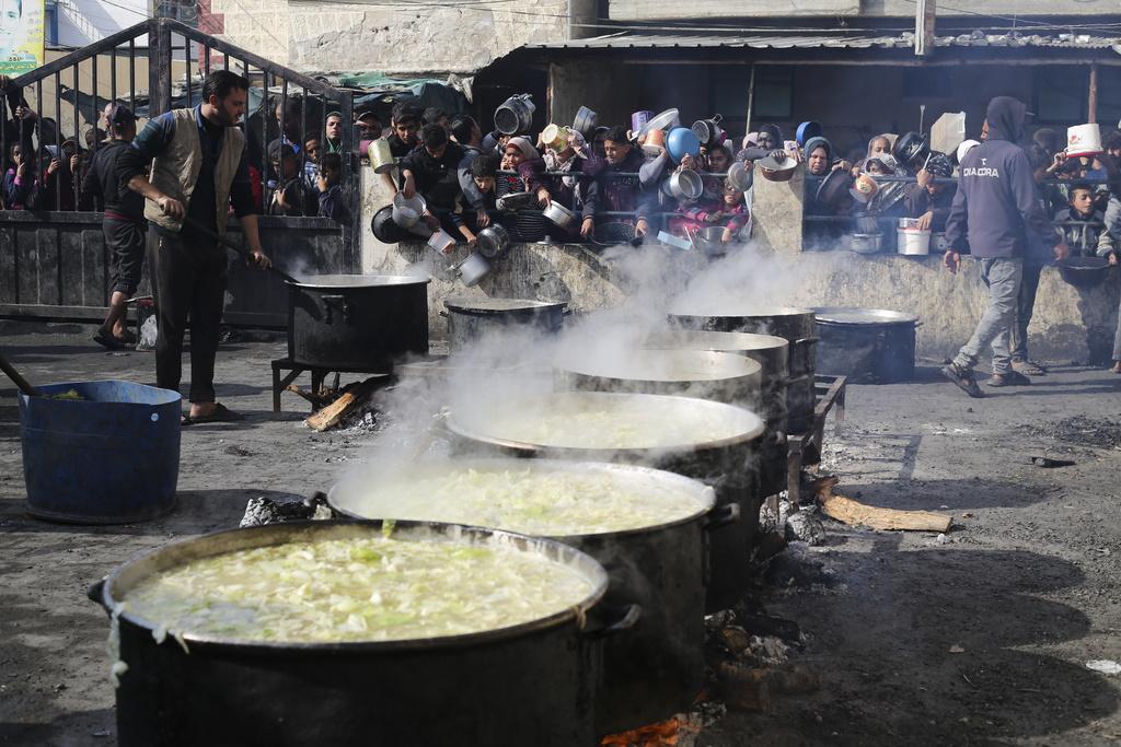 拉法邊境附近的加沙居民排隊取食物。(美聯社)