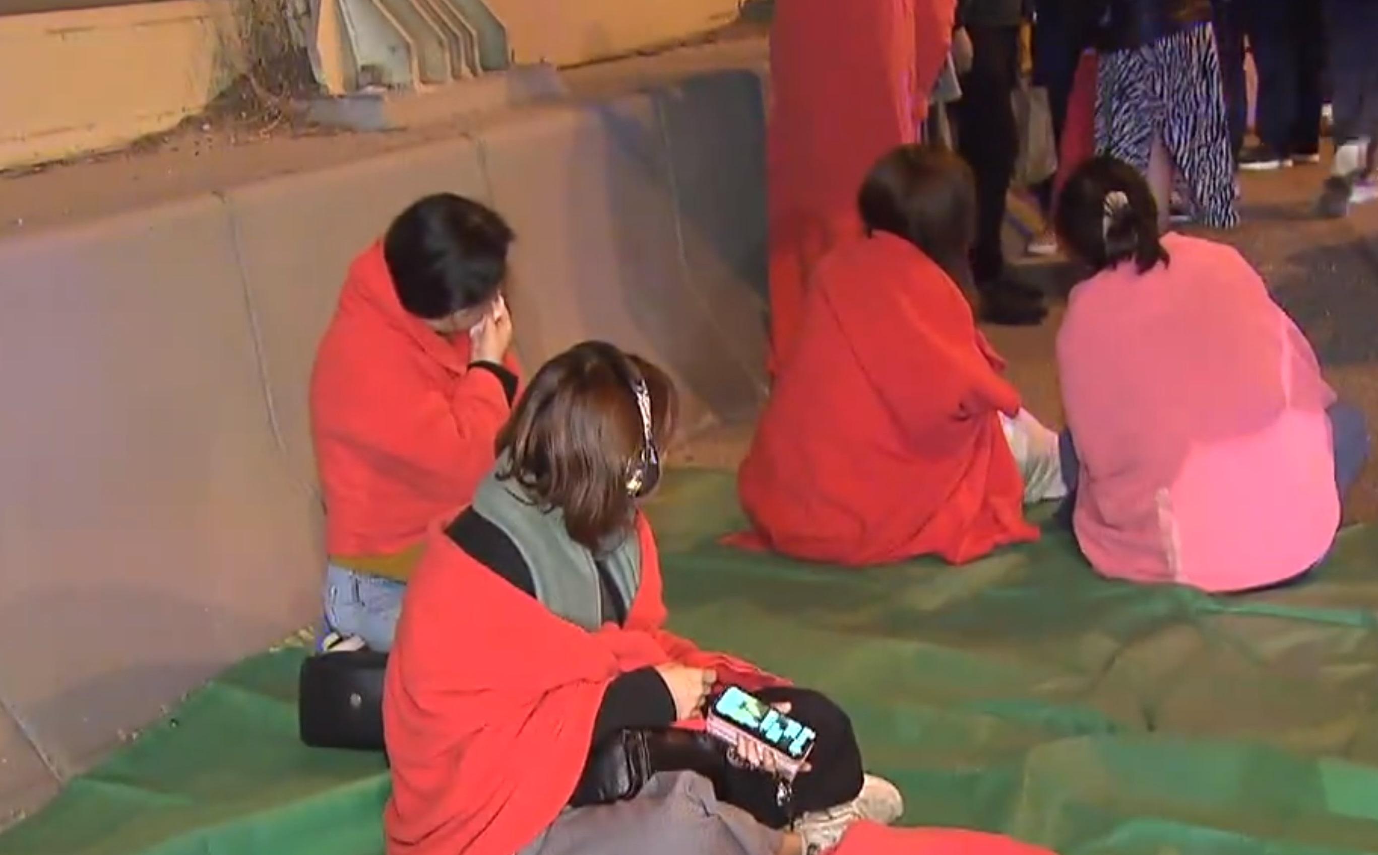 有乘客披上毛氈,在路邊等候救援。(新聞截圖)