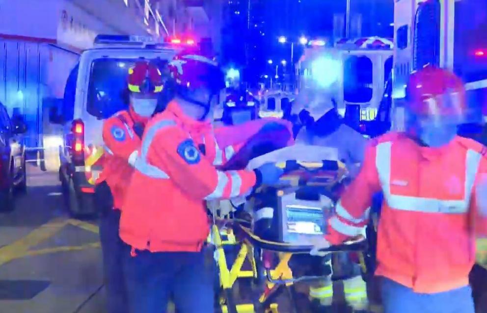 一名女子逃生時,昏迷倒臥在5至6樓梯間,由消防救出帶到後巷施救。(電視截圖)