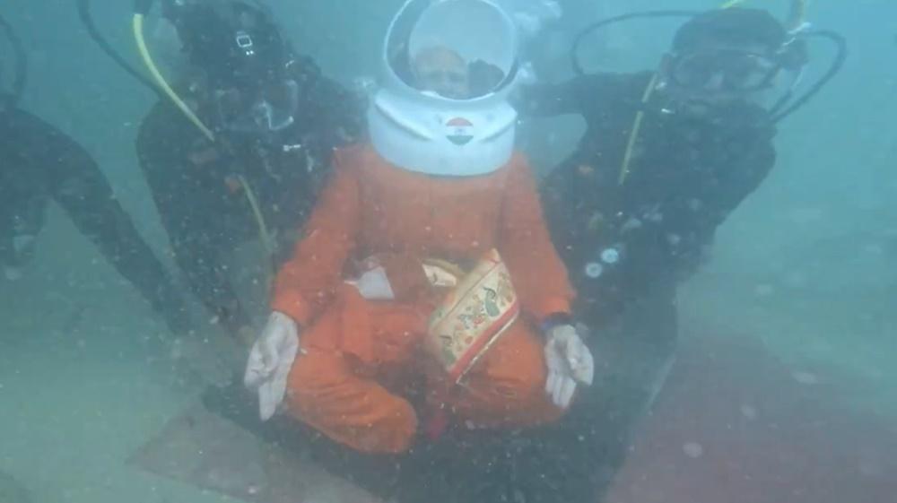 其後戴上頭盔形呼吸器,由多名潛水人員陪同下潛海底。(X)