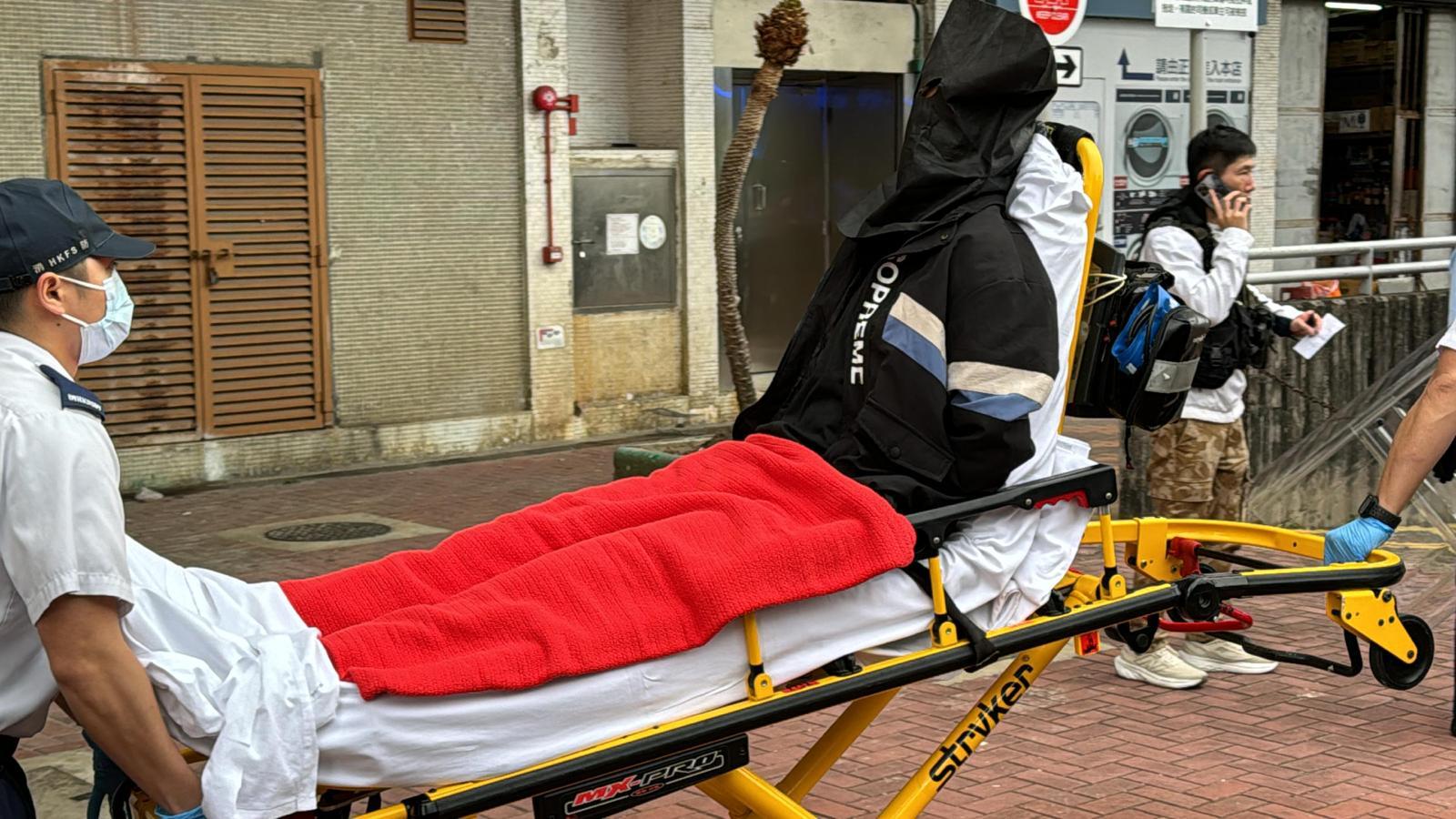 少年由黑布蒙頭送上救護車。