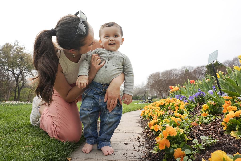 美國德州達拉斯一名母親周二帶兒子郊遊,享受冬季和暖。(美聯社)