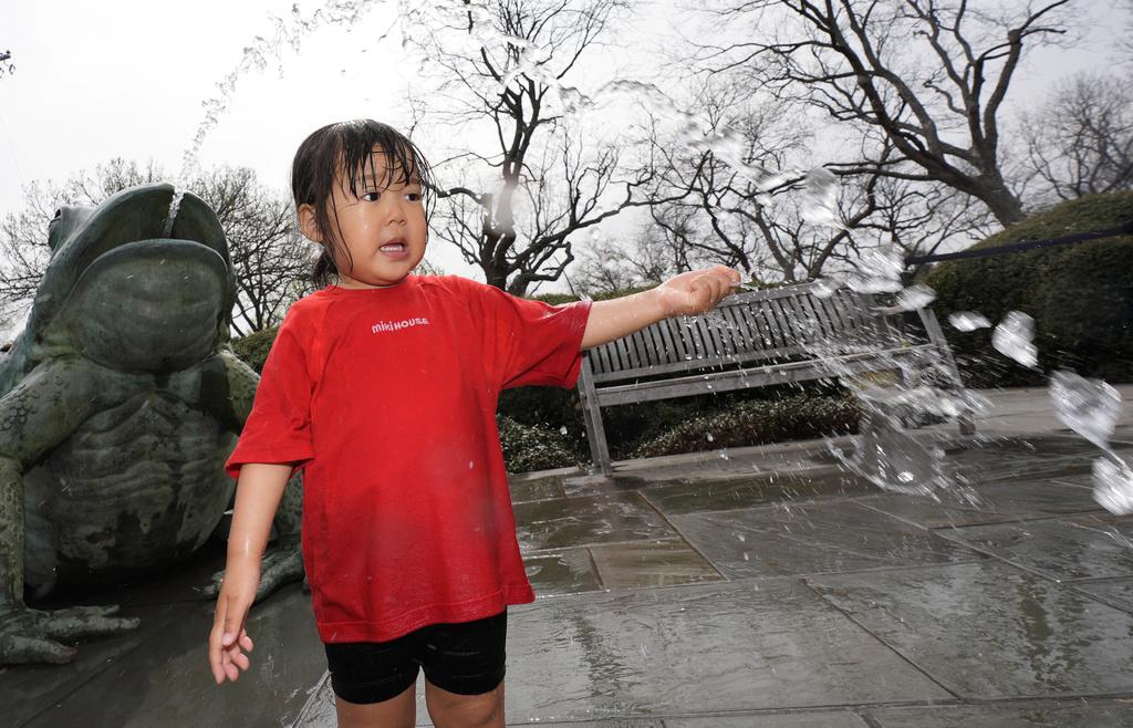 美國德州達拉斯周二天氣和暖,一名兩歲女童在公園戲水。(美聯社)