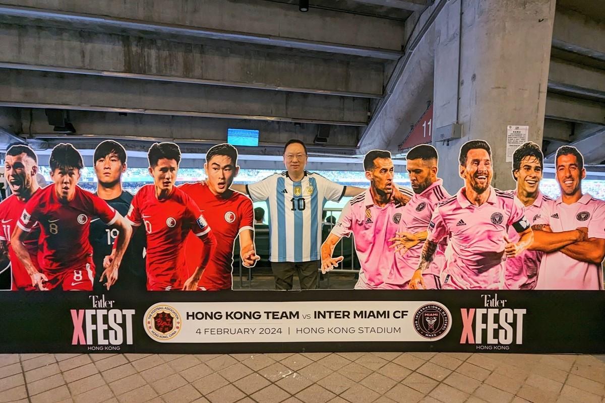 陳仲尼今日到大球場觀賽並與宣傳紙板留影,當時美斯的「頭部」仍在。(民建聯提供)