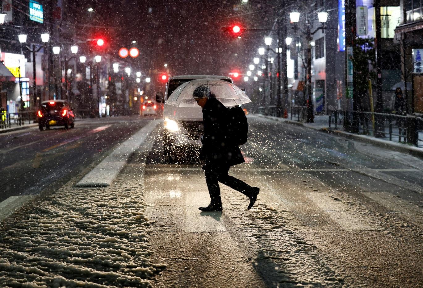 東京周一晚降雪,民眾外出時撐傘。(路透社)