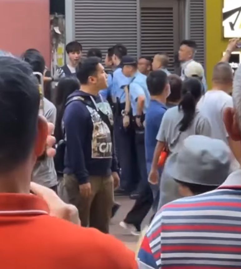 一名街頭歌手周日(24日)下午約4時在旺角朗豪坊對開演唱時,被多名警員包圍制服。(影片截圖)