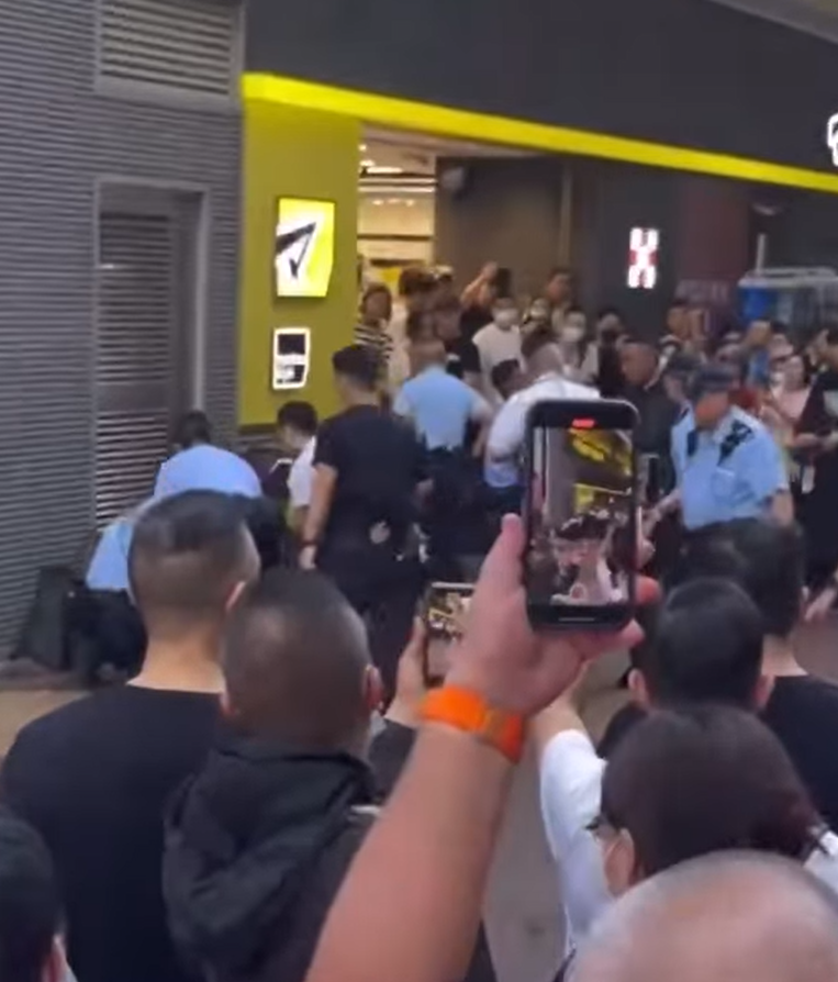 一名街頭歌手周日(24日)下午約4時在旺角朗豪坊對開演唱時,被多名警員包圍制服。(影片截圖)