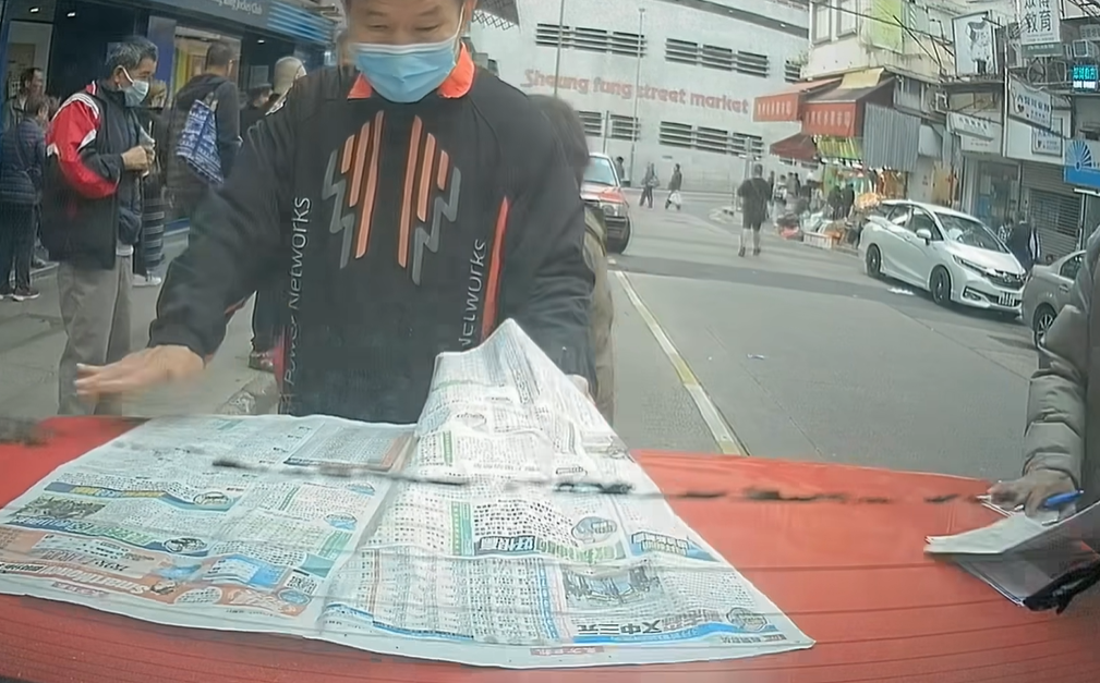 的士司機未有出言提醒便開車駛走,兩名馬迷隨即作出反應,將馬經及投注飛捉實,但仍有數張投注飛遺留在車尾冚上。(facebook群組「馬路的事討論區」影片截圖)