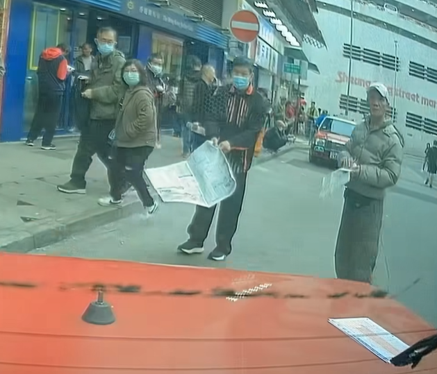 片段最後見到兩名馬迷呆若木雞,望住的士離開,其中一人更「手指指」,似乎對司機有不滿,及後拾回地上的投注飛。(facebook群組「馬路的事討論區」影片截圖)