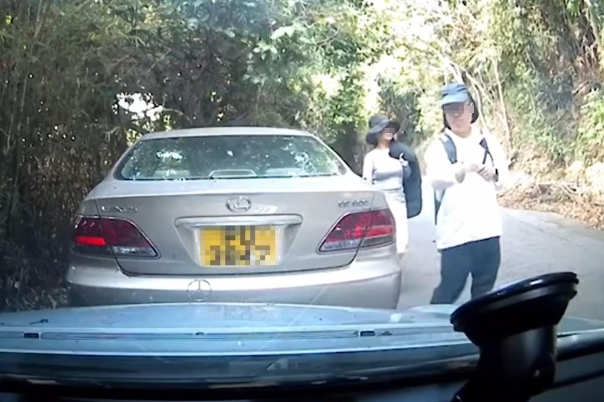 兩名相信是行山客的途人行經一輛平治私家車。(網上片段截圖)