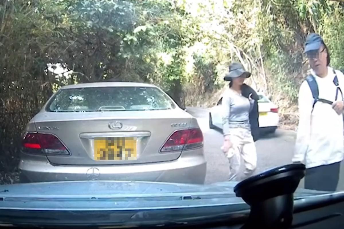兩名相信是行山客的途人行經一輛平治私家車。(網上片段截圖)