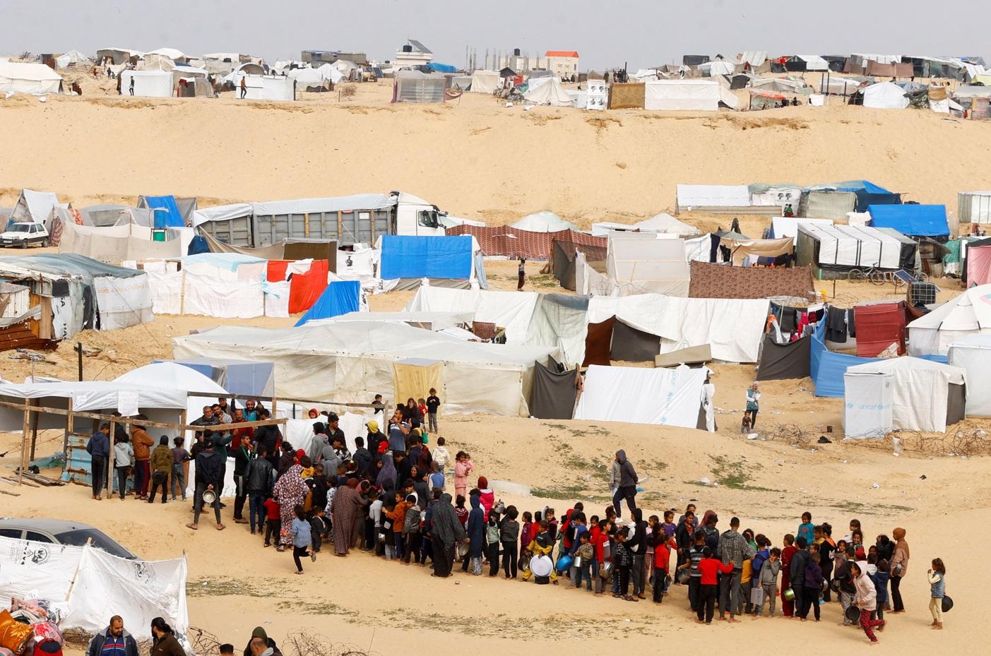 加沙南部拉法難民營居民上月底輪候領取糧食。(路透社)