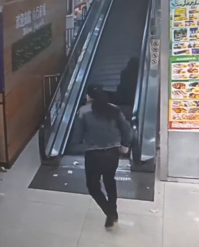 監視畫面顯示事主由自動扶梯上樓購物,涉事扶梯有一塊踏板「離奇消失」,她不幸地正好「踩空」,腿部隨即被捲入,電梯還繼續運行,有男職員見狀按下緊急煞停鈕,此時,女子腰部以下已被捲進扶梯。(影片截圖)