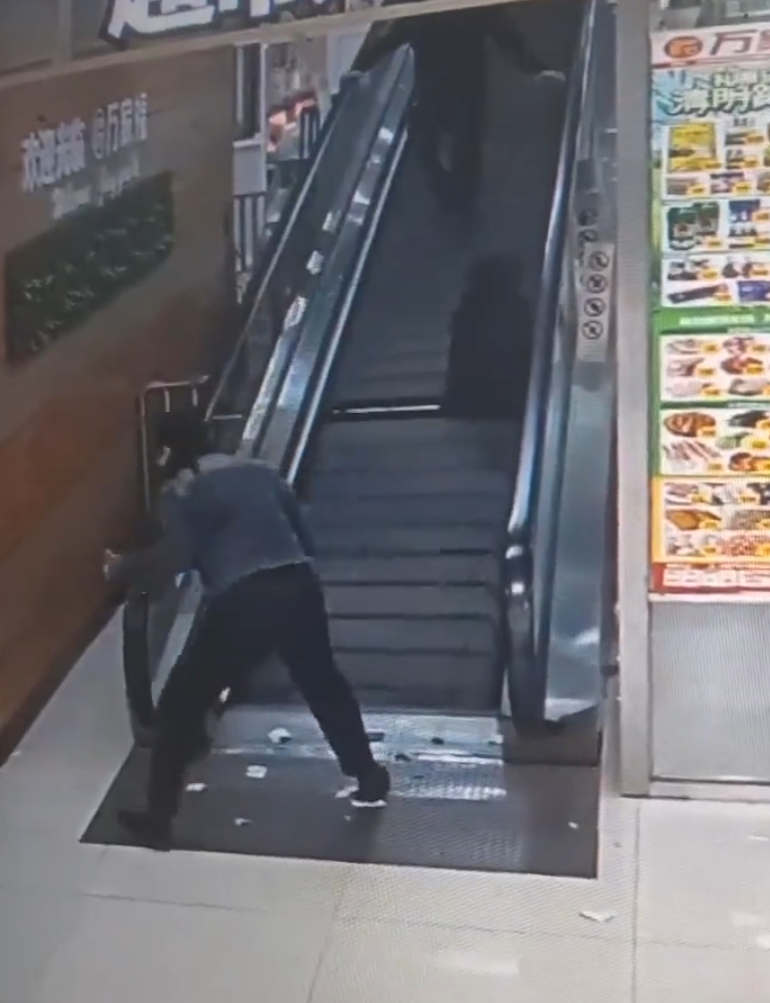 監視畫面顯示事主由自動扶梯上樓購物,涉事扶梯有一塊踏板「離奇消失」,她不幸地正好「踩空」,腿部隨即被捲入,電梯還繼續運行,有男職員見狀按下緊急煞停鈕,此時,女子腰部以下已被捲進扶梯。(影片截圖)