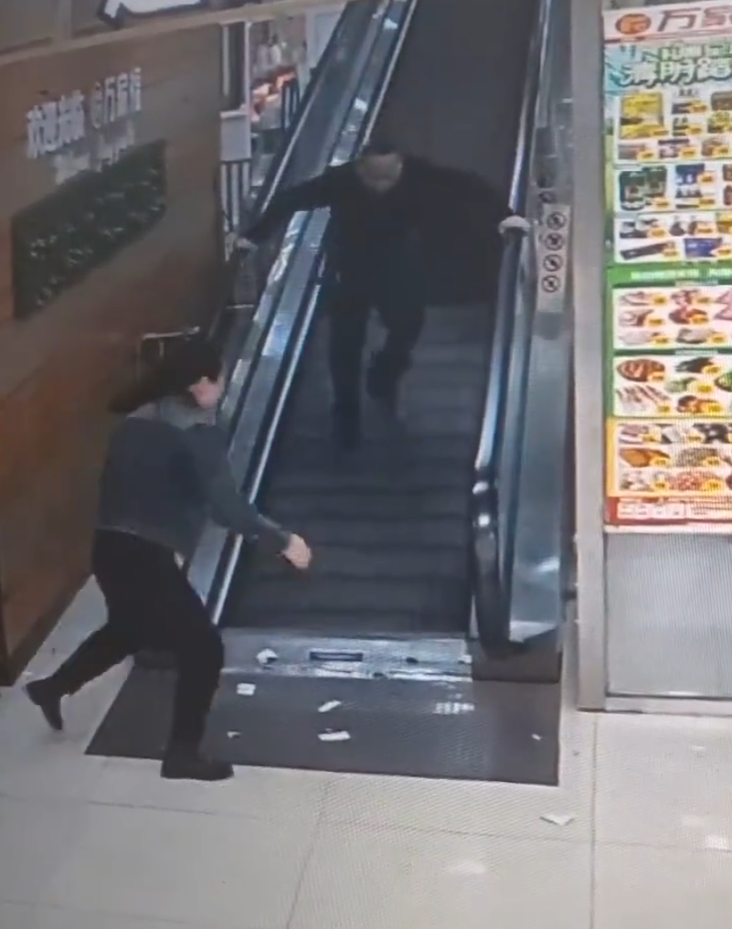 監視畫面顯示事主由自動扶梯上樓購物,涉事扶梯有一塊踏板「離奇消失」,她不幸地正好「踩空」,腿部隨即被捲入,電梯還繼續運行,有男職員見狀按下緊急煞停鈕,此時,女子腰部以下已被捲進扶梯。(影片截圖)