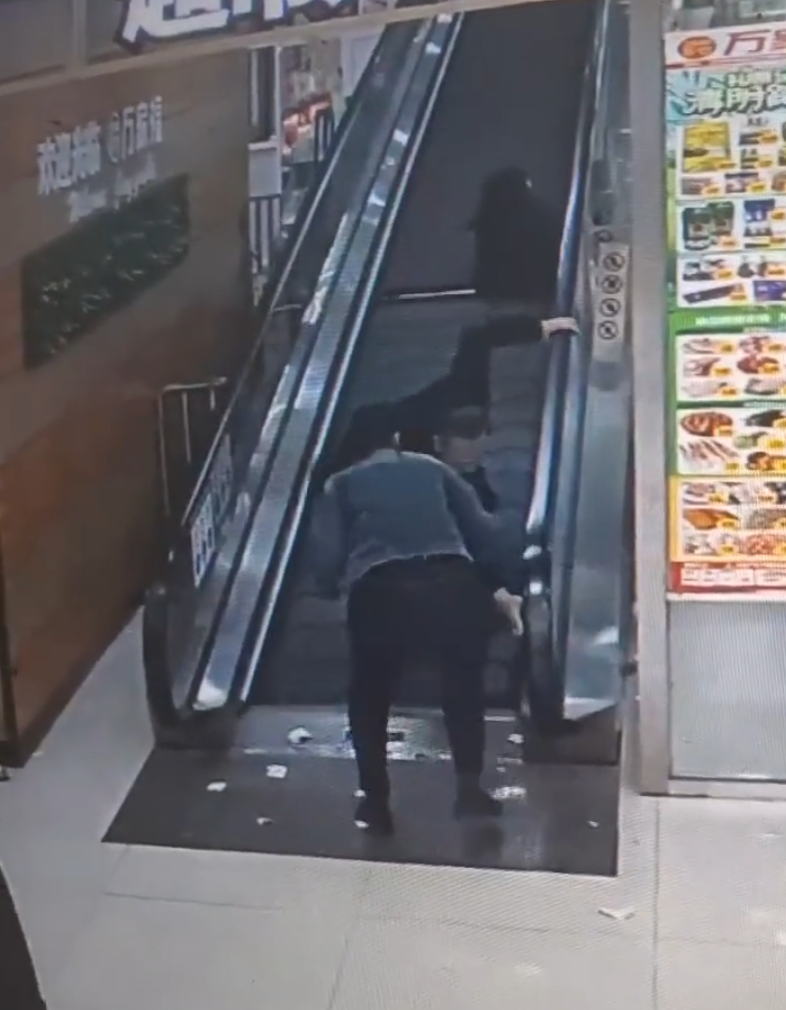 監視畫面顯示事主由自動扶梯上樓購物,涉事扶梯有一塊踏板「離奇消失」,她不幸地正好「踩空」,腿部隨即被捲入,電梯還繼續運行,有男職員見狀按下緊急煞停鈕,此時,女子腰部以下已被捲進扶梯。(影片截圖)