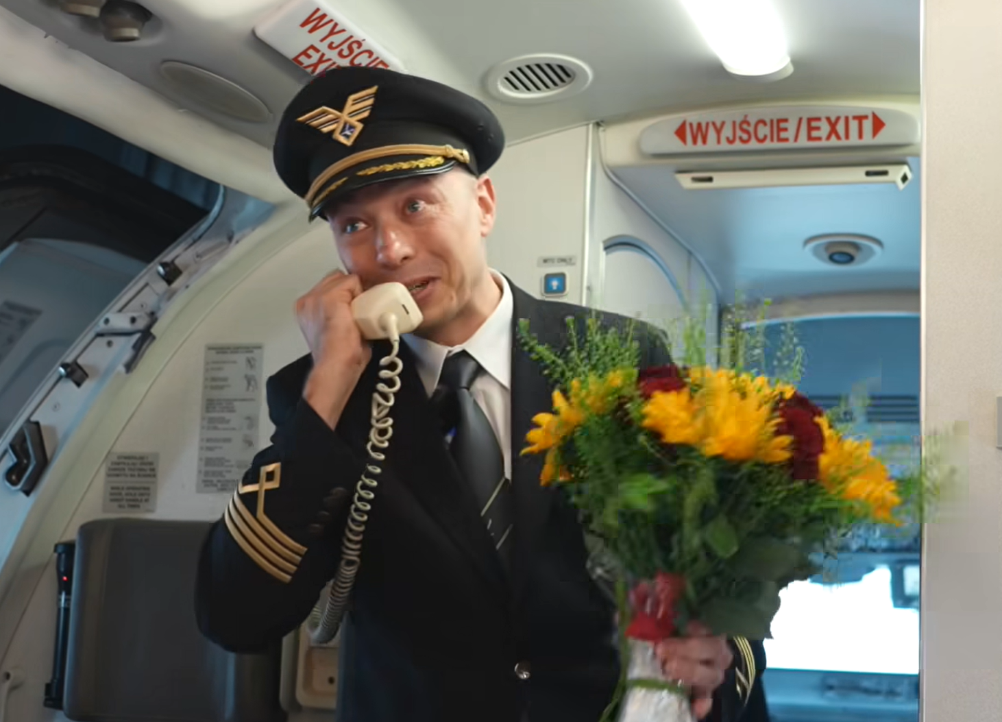 波蘭航空一班客機上演一幕浪漫求婚場面,駕駛航班的機長漢克向乘客廣播到一半時,單膝下跪向同機的空姐女友寶拉求婚。(波蘭航空fb影片截圖)