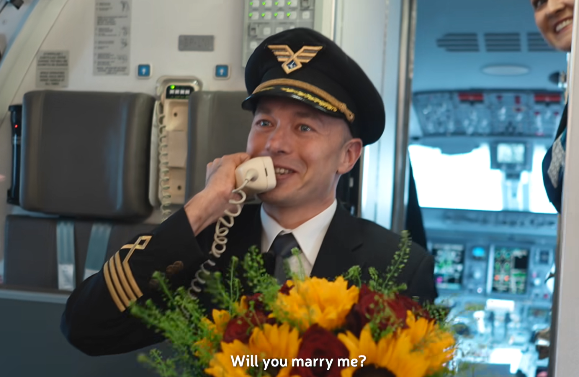 波蘭航空一班客機上演一幕浪漫求婚場面,駕駛航班的機長漢克向乘客廣播到一半時,單膝下跪向同機的空姐女友寶拉求婚。(波蘭航空fb影片截圖)