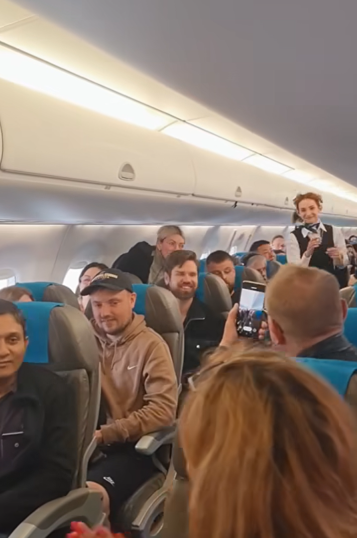 波蘭航空一班客機上演一幕浪漫求婚場面,駕駛航班的機長漢克向乘客廣播到一半時,單膝下跪向同機的空姐女友寶拉求婚。(波蘭航空fb影片截圖)