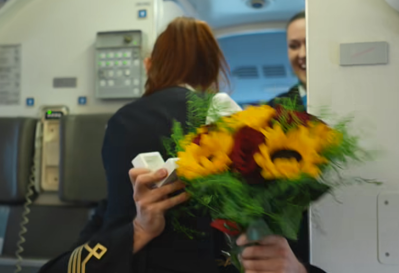 波蘭航空一班客機上演一幕浪漫求婚場面,駕駛航班的機長漢克向乘客廣播到一半時,單膝下跪向同機的空姐女友寶拉求婚。(波蘭航空fb影片截圖)