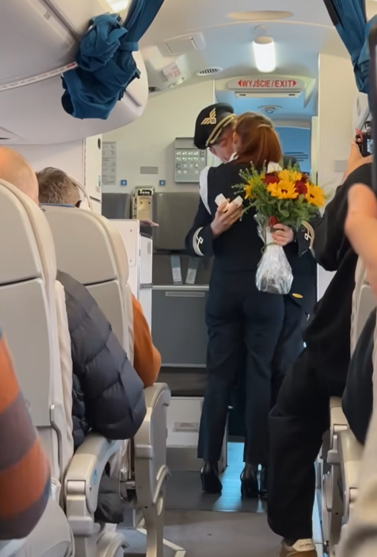 波蘭航空一班客機上演一幕浪漫求婚場面,駕駛航班的機長漢克向乘客廣播到一半時,單膝下跪向同機的空姐女友寶拉求婚。(波蘭航空fb影片截圖)