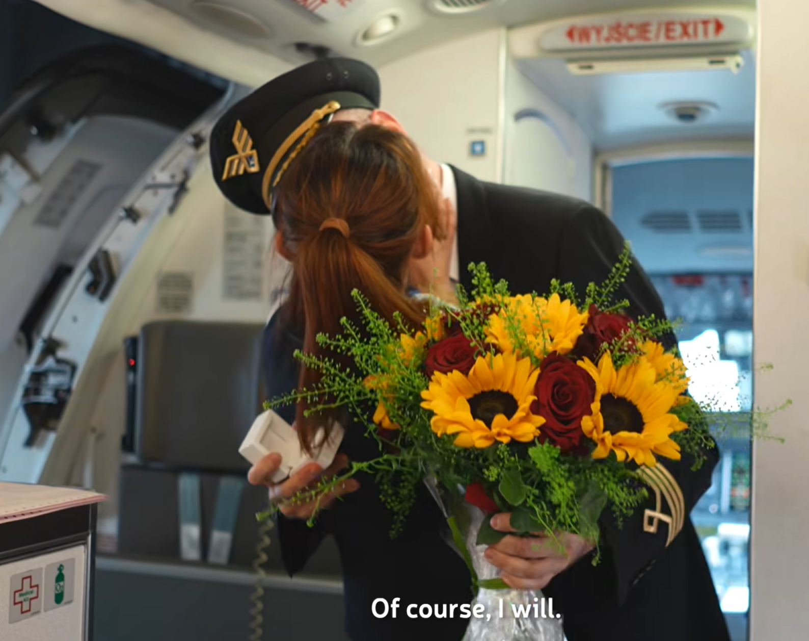 波蘭航空一班客機上演一幕浪漫求婚場面,駕駛航班的機長漢克向乘客廣播到一半時,單膝下跪向同機的空姐女友寶拉求婚。(波蘭航空fb影片截圖)