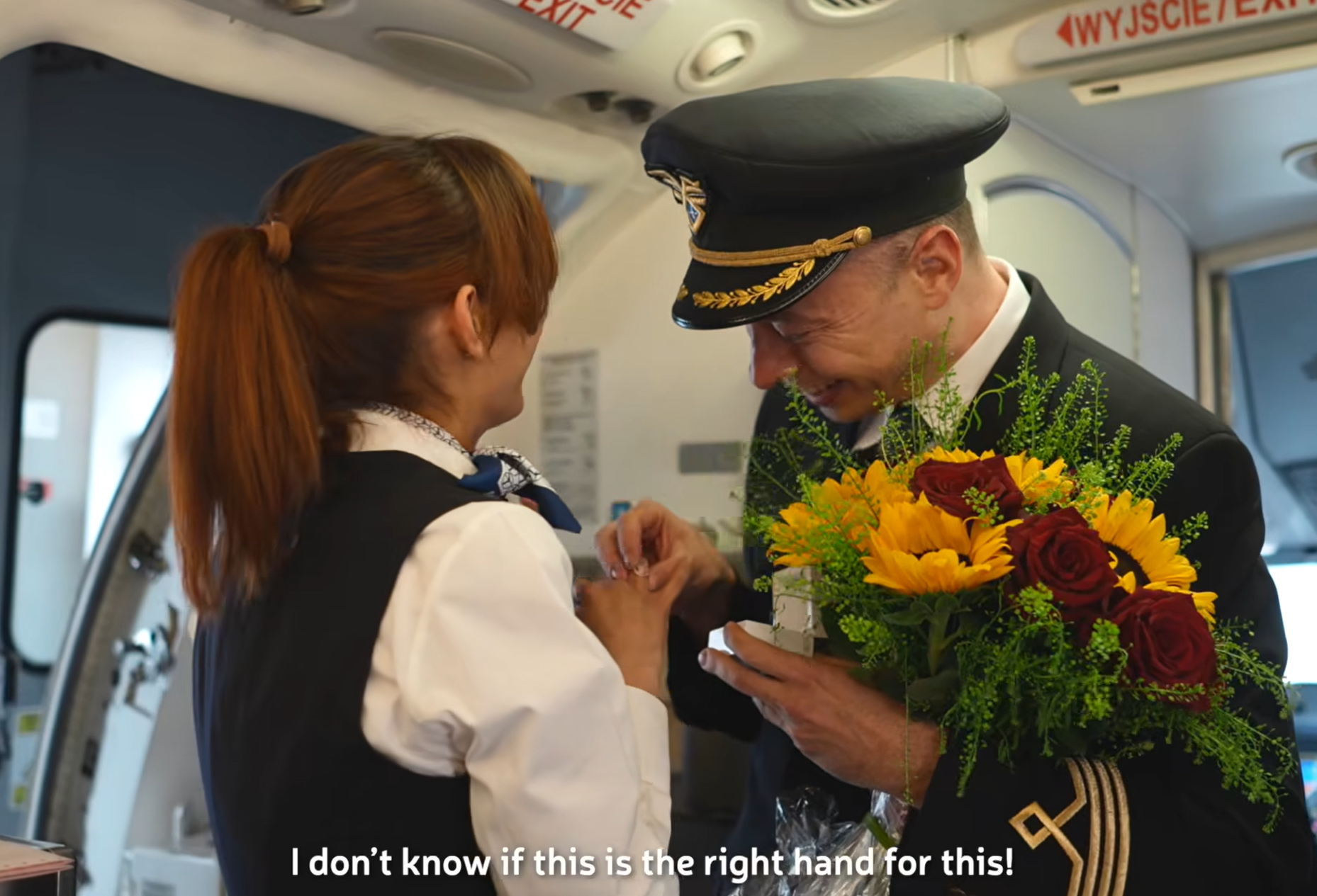 波蘭航空一班客機上演一幕浪漫求婚場面,駕駛航班的機長漢克向乘客廣播到一半時,單膝下跪向同機的空姐女友寶拉求婚。(波蘭航空fb影片截圖)
