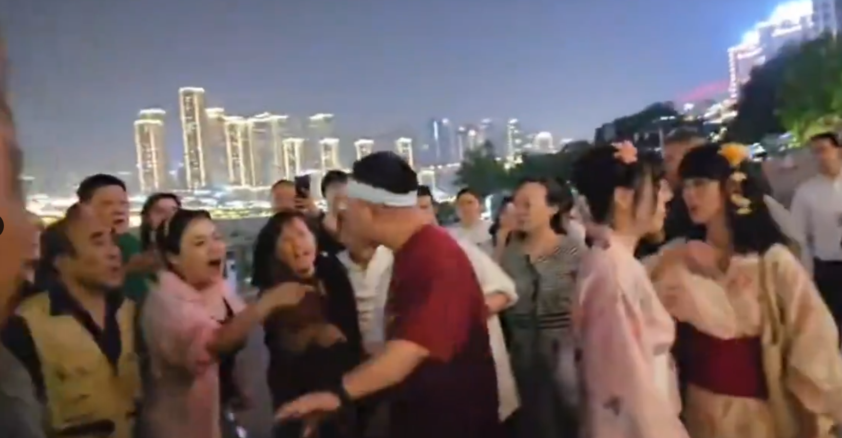 重慶市兩名女子上周六(27日)在南濱路博覽館前,穿着和服跳舞並拍攝影片,吸引路人圍觀,期間有一群長者聲討制止表不滿,雙方一度有肢體衝突,最終公安介入。(影片截圖)